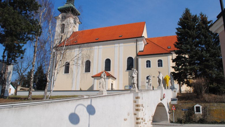 Wolkersdorf parish church, © Pfarrkirche Wolkersdorf Wolkersdorf parish church with statues on a bridge, blue sky.