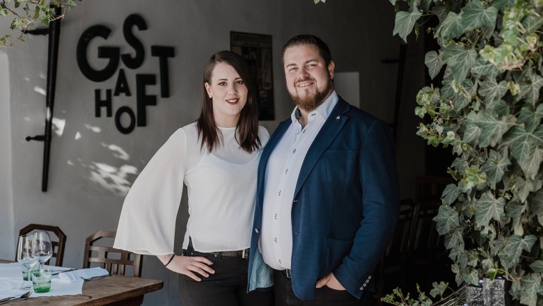 A team: Matthias Strunz & Julia Hochreiter, © Niederösterreich Werbung/David Schreiber A man and a woman stand smiling in front of a restaurant with the sign 'Gasthof'.