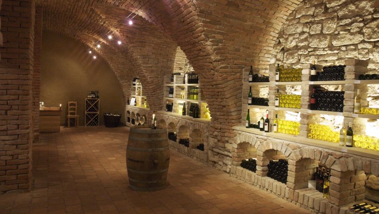 Castle wine cellar, © )Schlosshotel Mailberg Wine cellar with brick vaults and wine bottles on shelves.