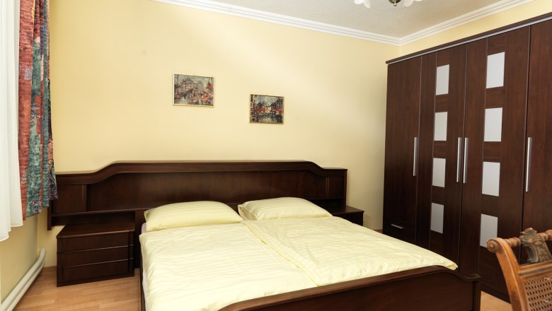 Comfort room, © Gasthof "Der Zesch" A cozy bedroom with a double bed, a large closet and two pictures on the wall.