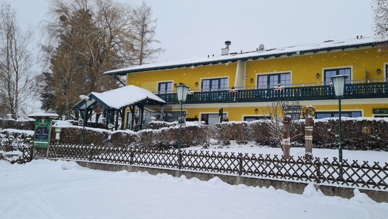 Krumbacherhof, © Wiener Alpen / Cornelia Schuh Yellow building in the snow with fence and trees.