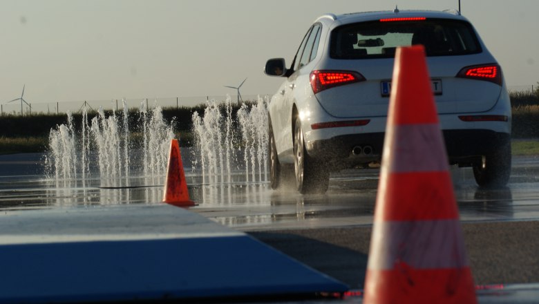 Driving Camp Pachfurth, © Driving Camp Pachfurth A car drives on a wet road with water fountains and traffic cones.