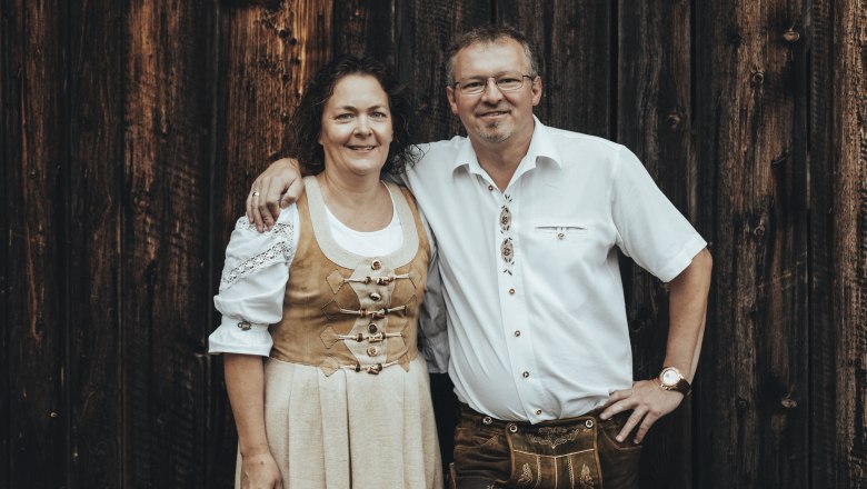 Innkeepers Silvia and Franz Schrammel, © Niederösterreich Werbung/David Schreiber A man and a woman in traditional costume in front of a wooden wall.