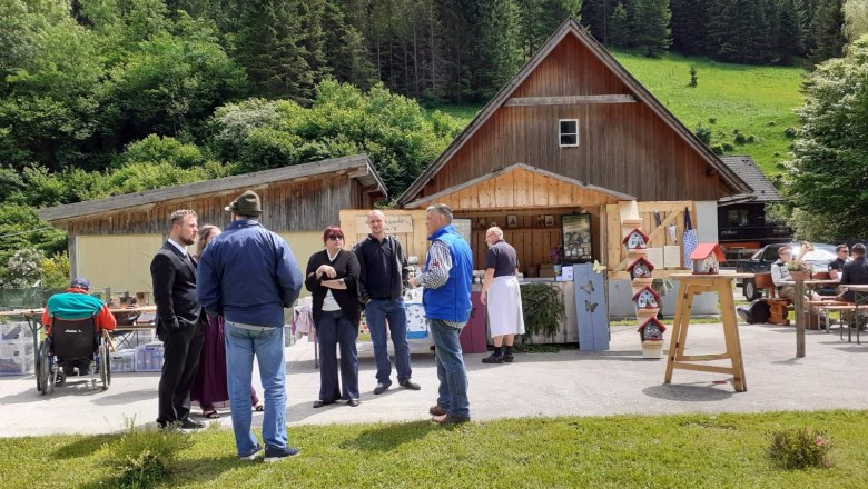 Regional art and culinary market, © Roland Kasper People at a market in front of wooden huts in a rural setting.