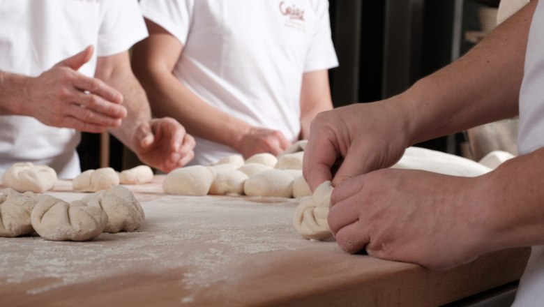 Genuine craftsmanship, © Geier.die Bäckerei Bakers form dough on a floured table.