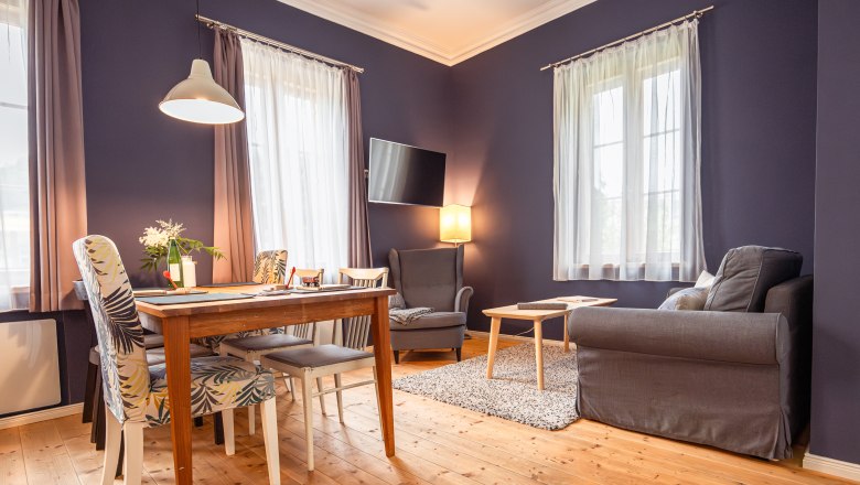 Vacation at the BAHNhof, © Niederösterreich Werbung / Maximilian Pawlikowsky Cozy living room with wooden floor, dining table, chairs, armchair and sofa.