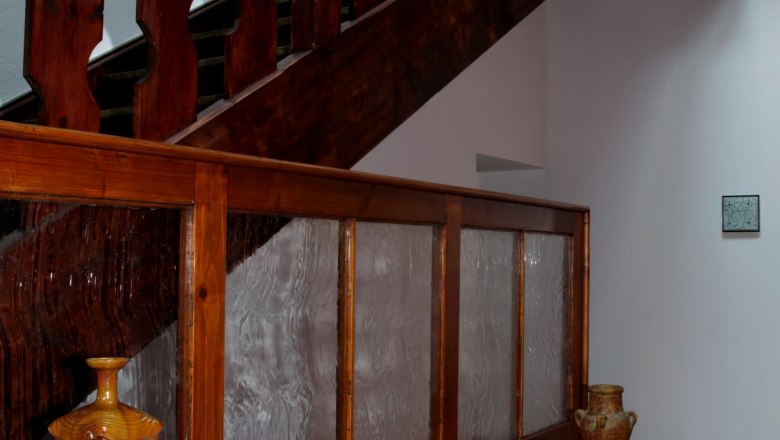 Staircase in loft 1, © Carlos de Mello Wooden staircase in a loft with decorative elements and books on a shelf.