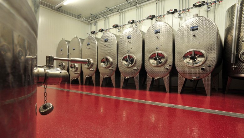 Modern cellar technology, © Harald Seymann Modern stainless steel tanks in a wine cellar with a red floor.