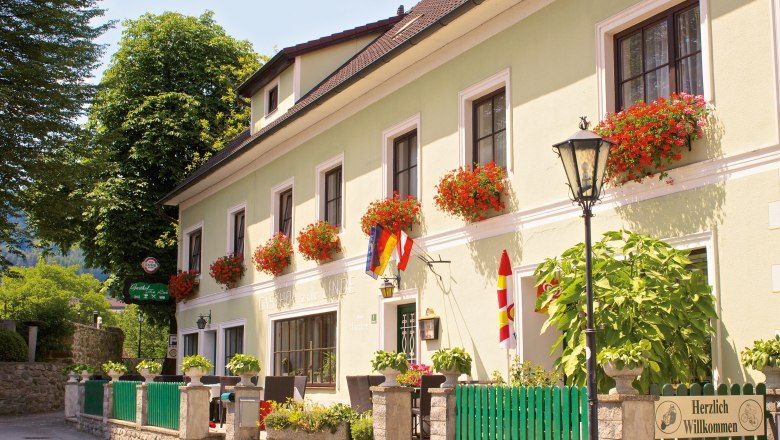 Gasthof-Hotel "Zur Linde", © Matthias Schön A traditional inn with a green façade and red flowers in flower boxes in front of the windows.