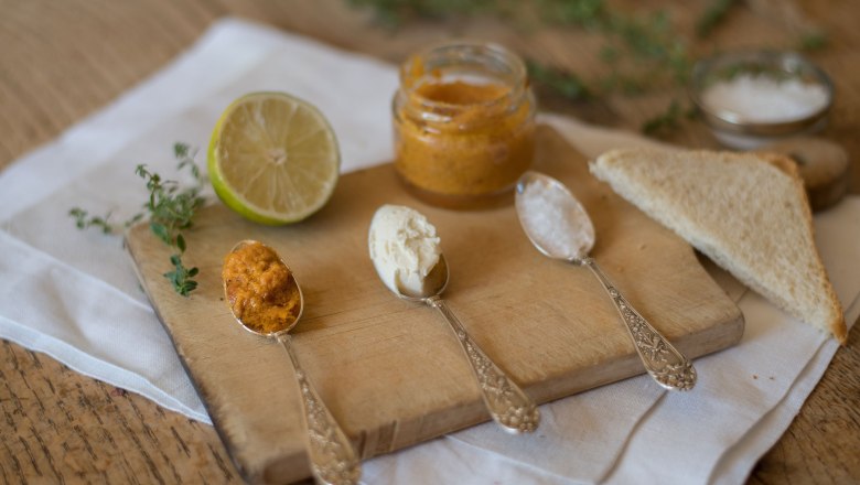 Carp caviar, © Freitag Fotografie Three spoons with different spreads on a wooden board, next to it half a lime and toast.