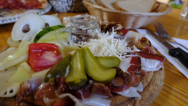 Symbol image, © Pixapay A wooden board with cold cuts, cheese, gherkins, tomatoes and onions, next to it a bread basket.