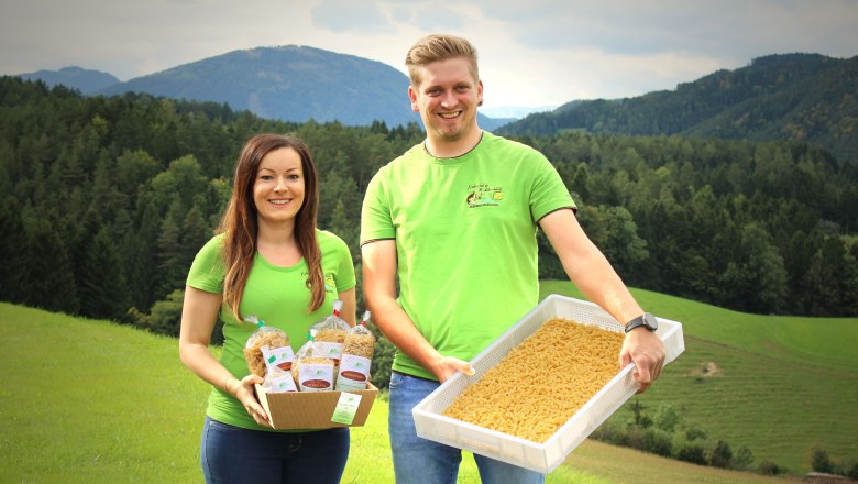 From the List pasta workshop, © Familie List Two people in green T-shirts present pasta in front of a mountain landscape.
