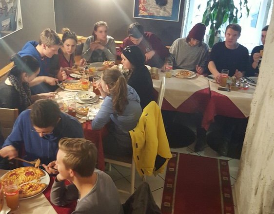 Pizzeria Borsalino, © Pizzeria Borsalino Group of people eating pizza in a cozy restaurant with cave walls.