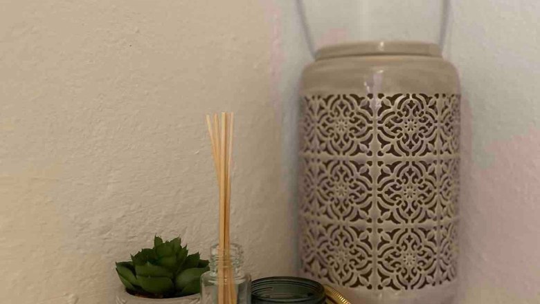 Decoration example, © Familie Stagard Decorative arrangement with scented sticks, candle, succulent and lantern on a white shelf.