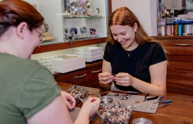 Making granite jewelry, © Waldviertel Tourismus, Matthias Streibel Two women make jewelry from granite stones at a table.