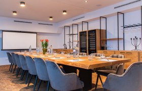 Wine house Nigl, © Weingut Nigl GmbH Modern conference room with large wooden table, gray chairs and presentation screen.