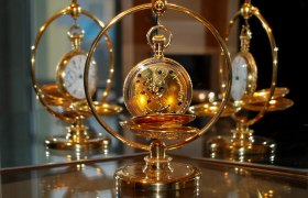 Karlstein Watch and Timekeeping Museum, © Uhrenmuseum Karlstein Golden pocket watch in a decorative stand, reflected in a mirror.