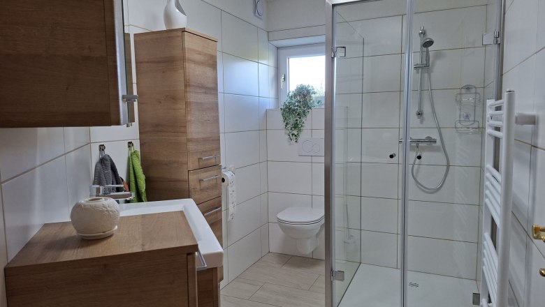 Shower, © Ferienwohnung Penz Stolzenthal, Fotograf Hermine Penz Modern bathroom with shower, WC and wooden cabinets.
