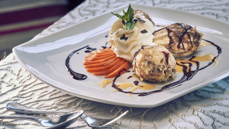 Malakoffnockerl, © Niederösterreich Werbung/Andreas Hofer A dessert plate with Malakoffnockerl, cream, chocolate sauce and decorative fruit.