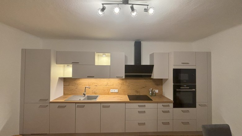 Kitchen, © Michael Hofer Modern kitchen with white cupboards, wooden worktop and built-in appliances.