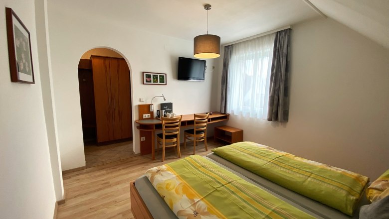 Double room, © Trachsler A cozy double room with two beds, desk, chairs and a TV on the wall.