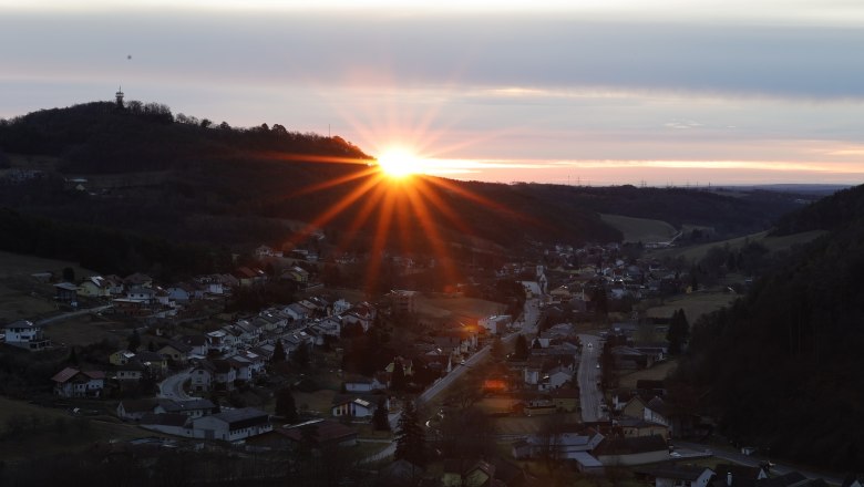 Sunrise behind the Keltenberg, © Marktgemeinde Schwarzenbach, Helmut Karner Sunrise behind a hill with a village in the foreground.