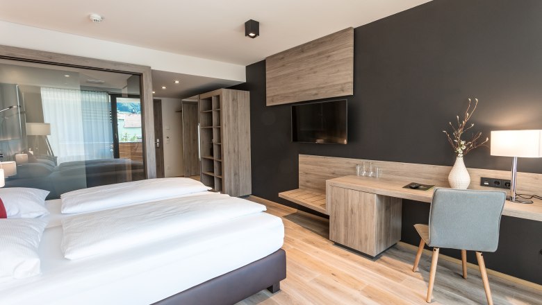 Room example 2 Weinlodge Wachau, © KASTNER NEW MEDIA - kastner.tv Modern furnished hotel room with double bed, desk, chair and flat screen TV on the wall.