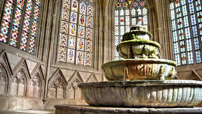 Well house, © Stift Heiligenkreuz An old fountain in a Gothic building with stained glass windows.