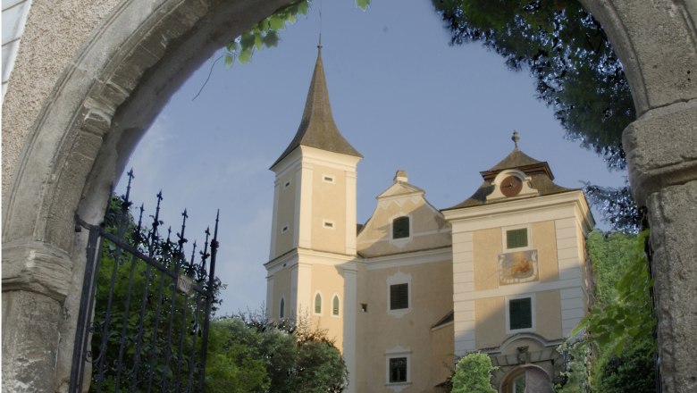 CastleMühlbach, © Gemeinde Hohenwarth-Mühlbach a.M. Mühlbach Castle behind a stone archway with a wrought-iron gate.