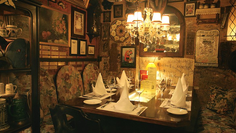 Marchfelderhof, © Gault Millau Comfortably decorated restaurant with a table setting, chandelier and pictures on the walls.