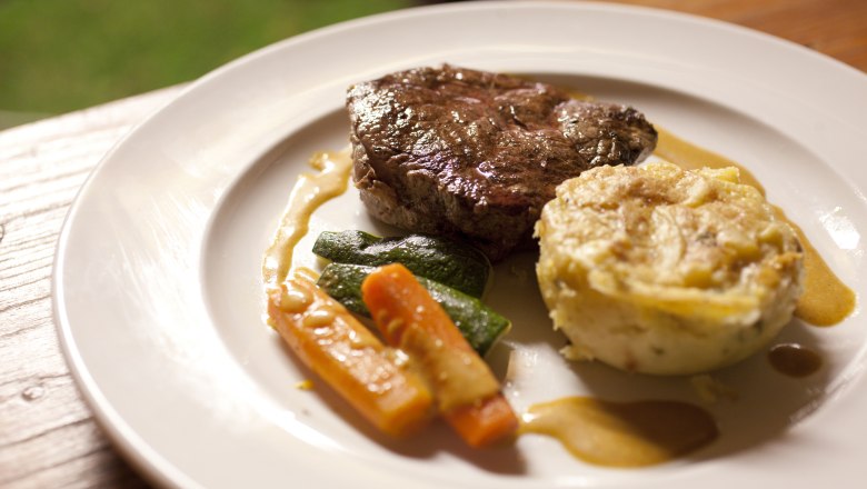Good food in the beer island, © Weinviertel Tourismus GmbH / Wurnig A plate with a piece of meat, vegetables and a potato gratin.