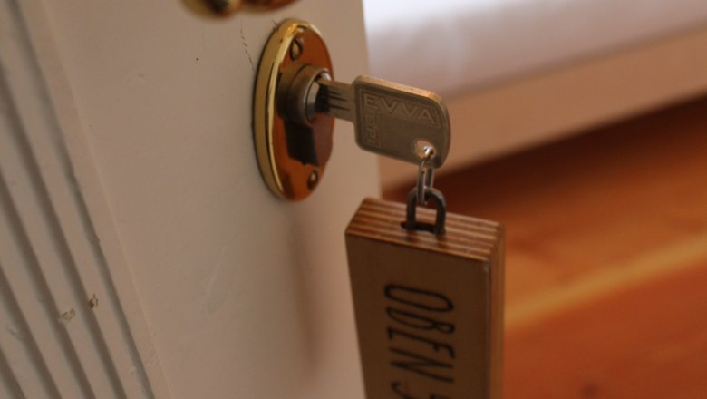 ABOVE, © OBENauf Close-up of a door handle with key and wooden tag with the inscription 'OBEN 5'.