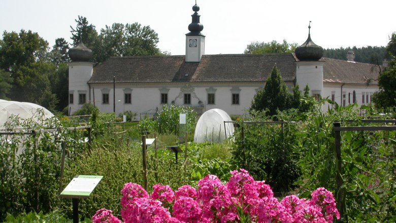 The baroque Noah's Ark castle garden, © Arche Noah Baroque building with onion domes behind a flowering garden.