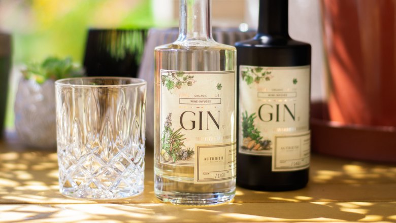 A Gin, © Bootleggers Manufaktur GmbH Two bottles of gin and a glass on a table outside.