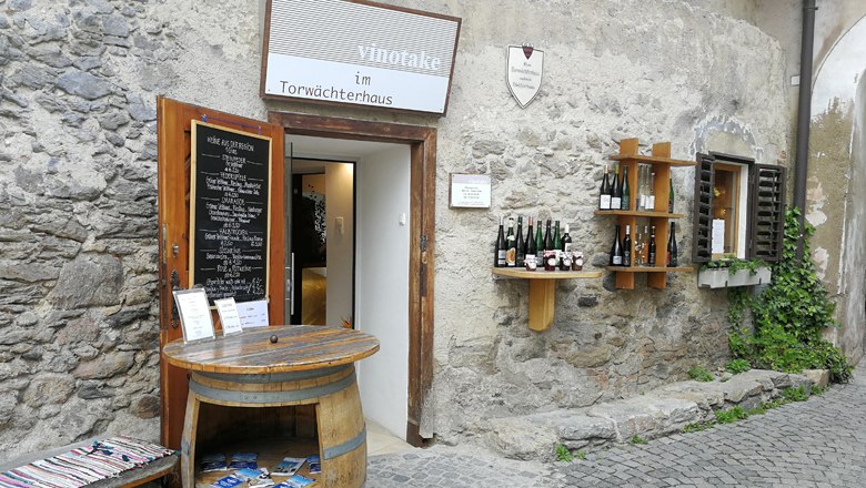 vinotake in the gatekeeper's house, © Roman Zöchlinger Entrance to a wine store in an old stone building with wine barrels and bottles on the wall.