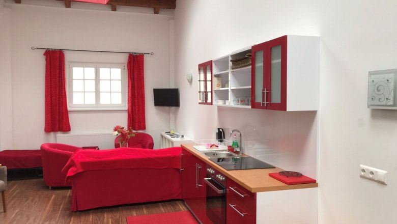 Kitchen in loft 2, © Konstantin Hübner Modern loft kitchen with red accents and wooden floor.