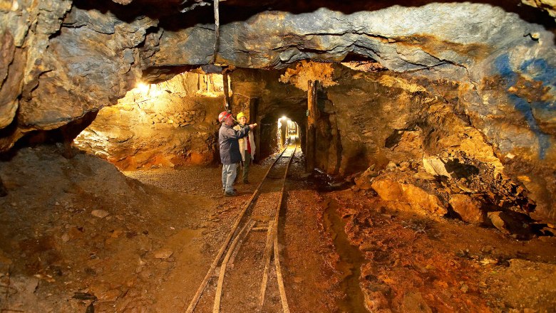 Grillenberg show mine, © Gemeinde Payerbach, Foto Franz Zwickl Interior view of an illuminated mine tunnel with two people in hard hats.