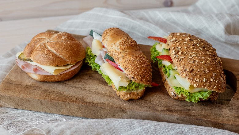 Snacks, © Koll GmbH Three sandwiches on a wooden board, with cheese, ham and salad.