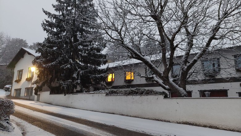 TDR-WelserhofWinter, © Nora Bartfai Winter street scene with snow-covered trees and illuminated windows.