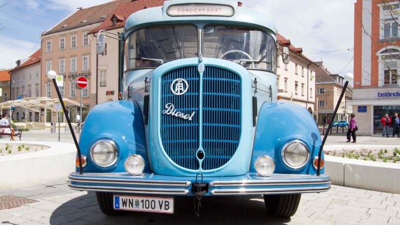 Vintage bus from 1961, © Michael Weller A blue vintage bus from 1961 is parked on a square in front of buildings.