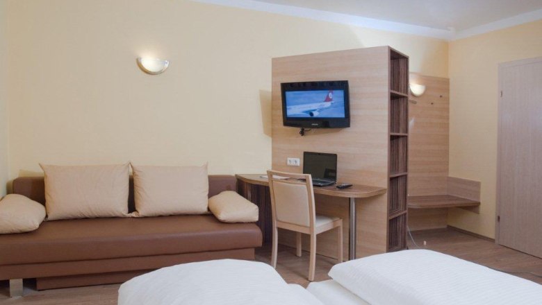 Hotel Radlinger, © Hotel Radlinger Hotel room with sofa, desk, TV and bed.