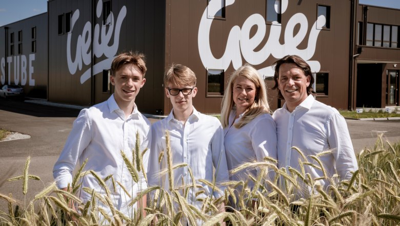 Family Geier, © Geier.die Bäckerei Four people in white clothing are standing in front of a building with the sign 'Geier'.