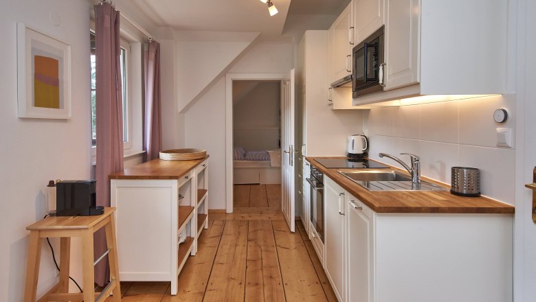 Top 2 - Kitchen, © VP FeWo OG Modern kitchen with wooden worktops, white cupboards and appliances.