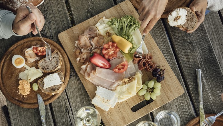 Heurigen snack, © Weinviertel Tourismus GmbH / Sophie Menegaldo Wooden table with snack, wine and bread.