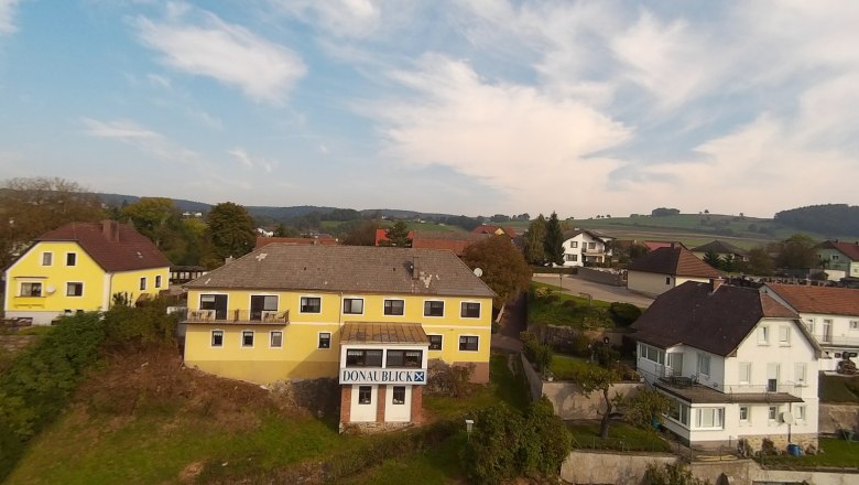 Exterior view4, © Gasthof Donaublick Landscape with yellow and white houses, blue sky, hills in the background.
