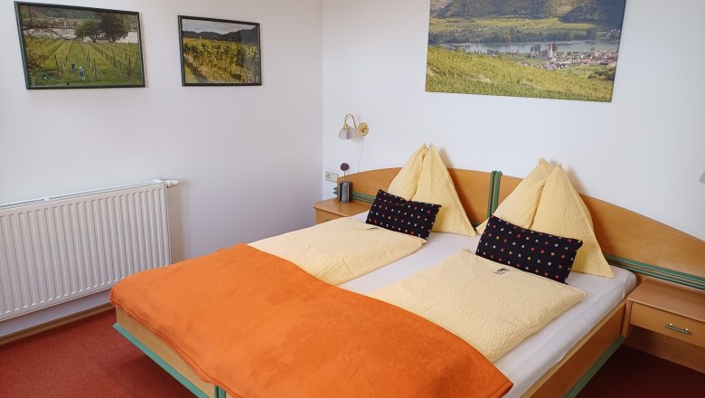 House Barbara_room example, © Haus Barbara Cozy hotel room with double bed, orange ceiling and landscape pictures on the wall.