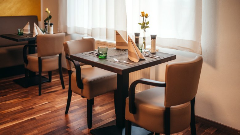 Stop off and enjoy, © Niederösterreich Werbung/Daniela Führer Cozy restaurant with wooden floor, laid table and flowers.