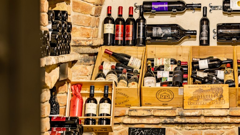 Wine cellar, © Christian Kremsl Wine bottles in a rustic wine cellar with brick walls.