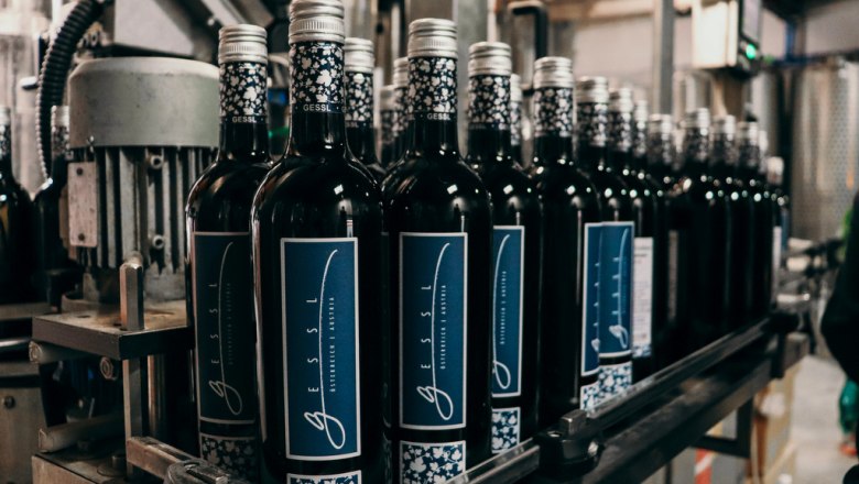 Outstanding wines, © Bio Weingut Gessl Wine bottles on a conveyor belt in a bottling plant.