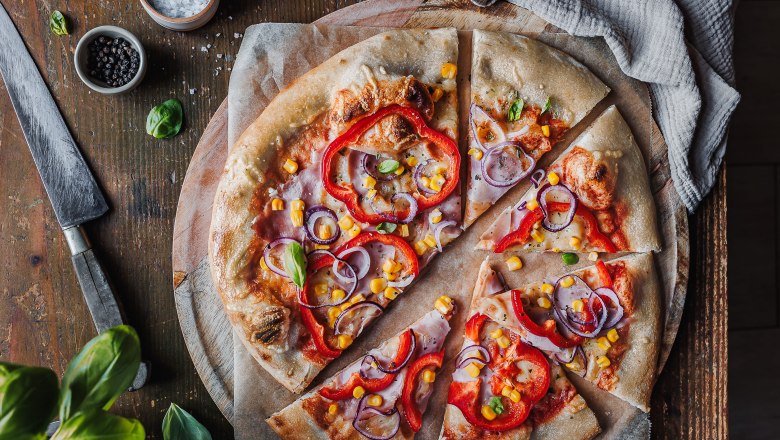 Pizza, © Koll GmbH Pizza with peppers, onions and corn on a wooden board.